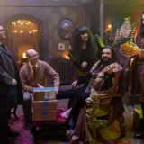 Die Besetzung von "What We Do in the Shadows" in einem opulenten Raum. Nandor sitzt auf einem Thron, während Nadja und Laszlo daneben stehen. Guillermo und Colin Robinson sind ebenfalls anwesend.