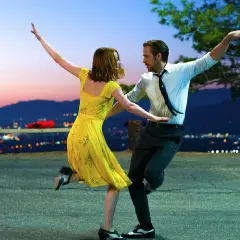 Ein Paar tanzt im Abendrot vor einer Stadtkulisse. Perfekt für gute Laune Filme!