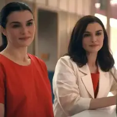 Zwei Frauen, die sich ähneln, stehen nebeneinander. Die eine trägt ein rotes Oberteil, die andere einen beigen Blazer über einem roten Kleid. Sie sind Teil von "die unzertrennlichen serie".