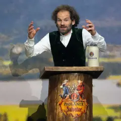 Ein Mann mit Lockenmähne und grünen Weste hält eine Rede am Nockherberg. Seine Gestik und Mimik lassen auf eine kritische Auseinandersetzung schließen.