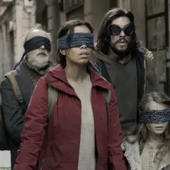 Die Besetzung von Bird Box: Eine Gruppe von Menschen, die mit verbundenen Augen durch eine Gasse gehen, um den unsichtbaren Gefahren zu entkommen.