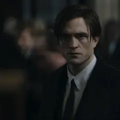 Robert Pattinson als der junge Batman, mit ernstem Blick und dunklem Anzug, inmitten einer Menge.