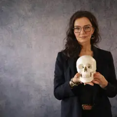 Frau mit Brille hält Totenkopf. Ein gutes stegreifrede beispiel, um über Vergänglichkeit zu sprechen.