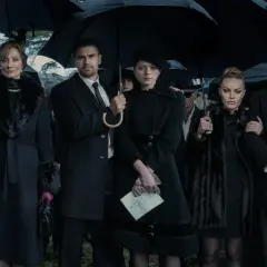 Die Besetzung von The Gentlemen bei einer Beerdigung, alle unter schwarzen Regenschirmen.