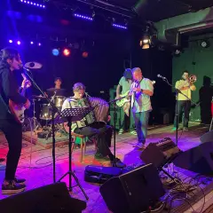 Band jammt Musik, die Bedeutung von Gemeinschaft und Kreativität. Akkordeon, Gitarre, Trompete und Schlagzeug.