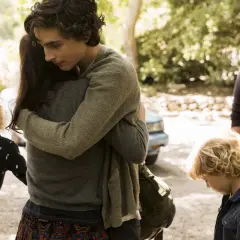 Ein schöner Junge umarmt jemanden in diesem emotionalen Film. Zwei Kinder und ein Mann stehen daneben.