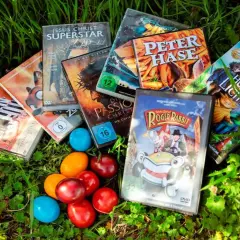 Osterfilm-Spaß für Kinder: DVDs wie "Peter Hase" und "Roger Rabbit" liegen neben bunten Eiern im Gras.