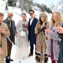 Die besetzung von der spitzname feiert eine Hochzeit im Schnee. Eine Braut mit Blumenstrauß, ein Bräutigam mit Schnurrbart und Gäste in Wintermänteln.