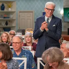 Ein Mann im Anzug steht vor einer Gruppe älterer Menschen, die applaudieren. Es sieht aus wie eine **Besetzung von undercover im Seniorenheim**.