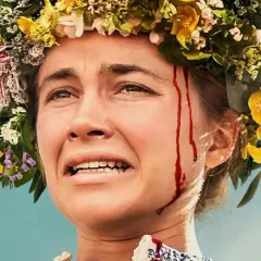 Nahaufnahme einer Frau mit Blumenkranz und Blutspuren im Gesicht. Die besetzung von Midsommar zeigt eine Frau in emotionaler Not.