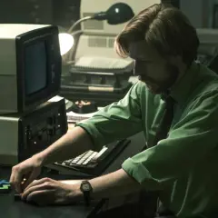 Mann mit Bart spielt mit Tetris-Steinen vor einem alten Computer. Ein Moment aus dem "Tetris"-Film.