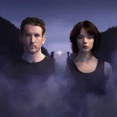 Ein Mann und eine Frau stehen im Nebel vor einer düsteren Berglandschaft. Das ist ein Bild aus "The George Film".