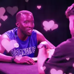 Zwei Männer im Gespräch, umgeben von rosa Herzen. Einer trägt ein blaues Tanktop mit "Los Angeles". Der Vibe ist wie ein "roasted jugendsprache" Date.