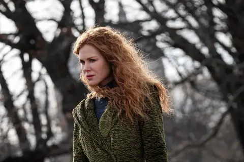 Nicole Kidman mit roten Haaren, im grünen Mantel, blickt nachdenklich in die Ferne. Ein Moment des "the undoing" in der Natur.