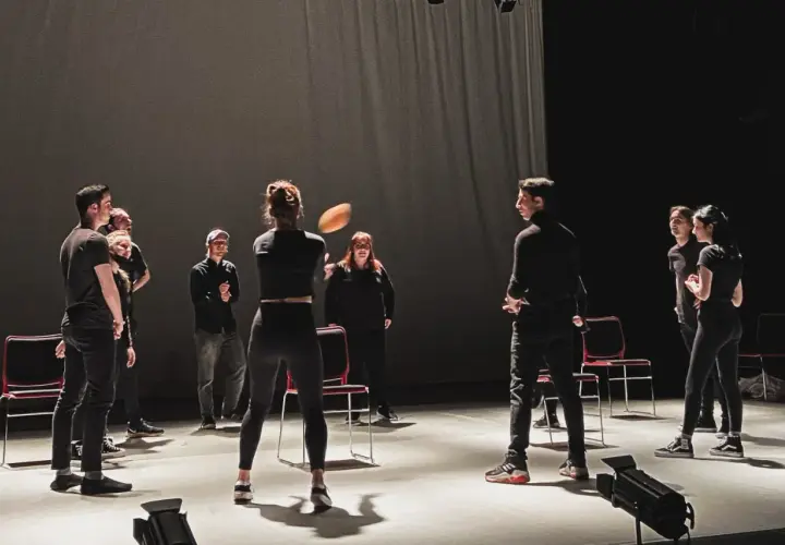Schauspieler proben auf der Bühne, eine Frau wirft einen Ball. Viele improtheater ideen entstehen in solchen Momenten.