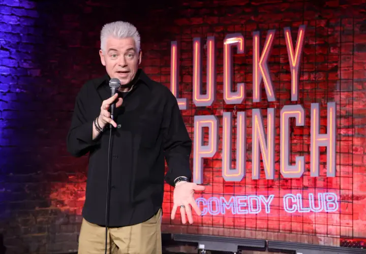 Ein Comedian mit grauem Haar steht auf der Bühne des "Lucky Punch Comedy Club" und erzählt Witze.