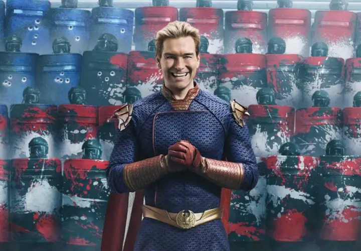 Homelander, Teil der Besetzung von The Boys, steht vor einer Reihe von Riot-Schutzschilden, die mit roten und blauen Farbspritzern verziert sind.