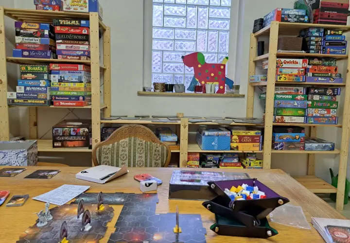 Regale voller Brettspiele für sprachspiele erwachsene. Ein Spielbrett mit Figuren liegt auf dem Tisch.