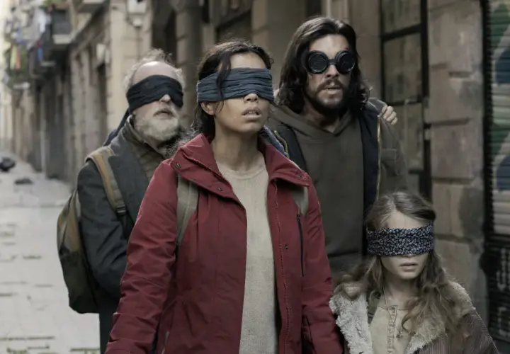 Die Besetzung von Bird Box: Eine Gruppe von Menschen, die mit verbundenen Augen durch eine Gasse gehen, um den unsichtbaren Gefahren zu entkommen.