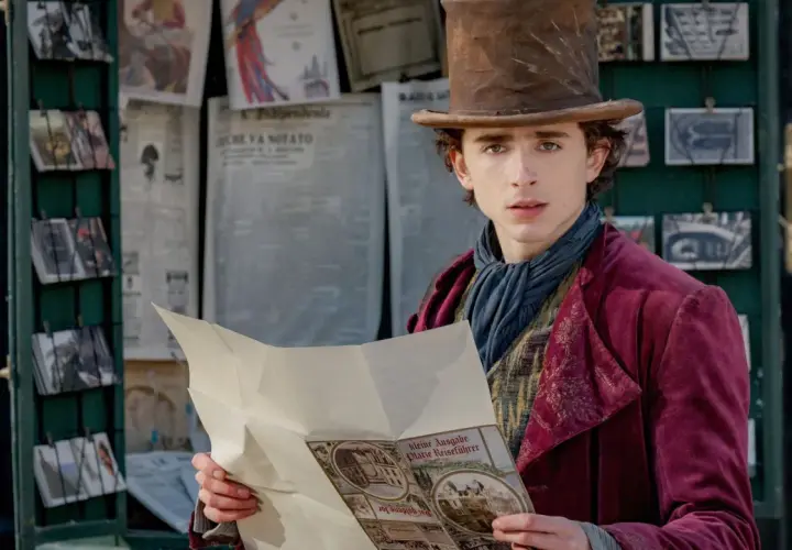 Timothée Chalamet als junger Willy Wonka, der in einem viktorianischen Outfit und mit einem Zylinder vor einem Zeitungskiosk steht und eine Broschüre liest. Die Besetzung von Wonka verspricht Magie.
