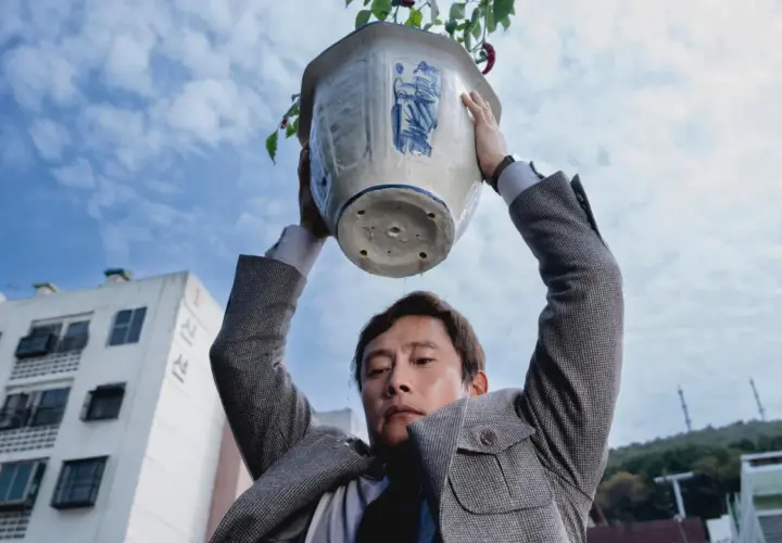 Ein Mann hält einen Blumentopf über seinem Kopf. Wasser tropft herunter. Eine Szene aus dem Film "No other choice".