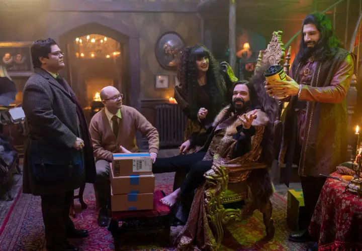 Die Besetzung von "What We Do in the Shadows" in einem opulenten Raum. Nandor sitzt auf einem Thron, während Nadja und Laszlo daneben stehen. Guillermo und Colin Robinson sind ebenfalls anwesend.
