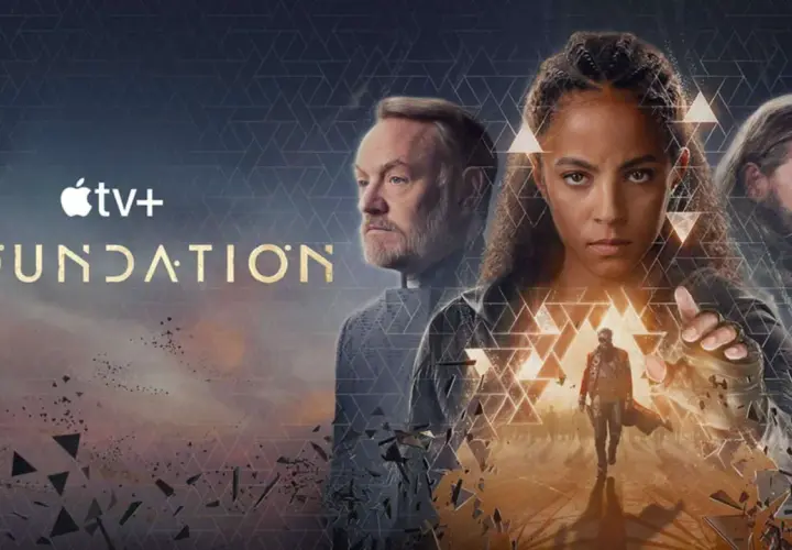 Apple TV+ "Foundation" Serie: Drei Hauptfiguren blicken ernst in die Ferne, während ein Mann im Vordergrund eine Hand ausstreckt.