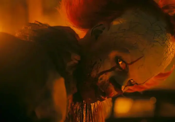 Pennywise, der Clown, blickt mit leuchtenden Augen aus dem Feuer. Willkommen in Derry, wo er auf seine Opfer wartet.