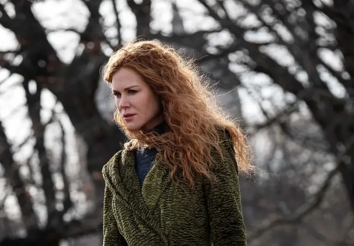 Nicole Kidman mit roten Haaren, im grünen Mantel, blickt nachdenklich in die Ferne. Ein Moment des "the undoing" in der Natur.