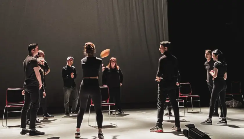 Schauspieler proben auf der Bühne, eine Frau wirft einen Ball. Viele improtheater ideen entstehen in solchen Momenten.