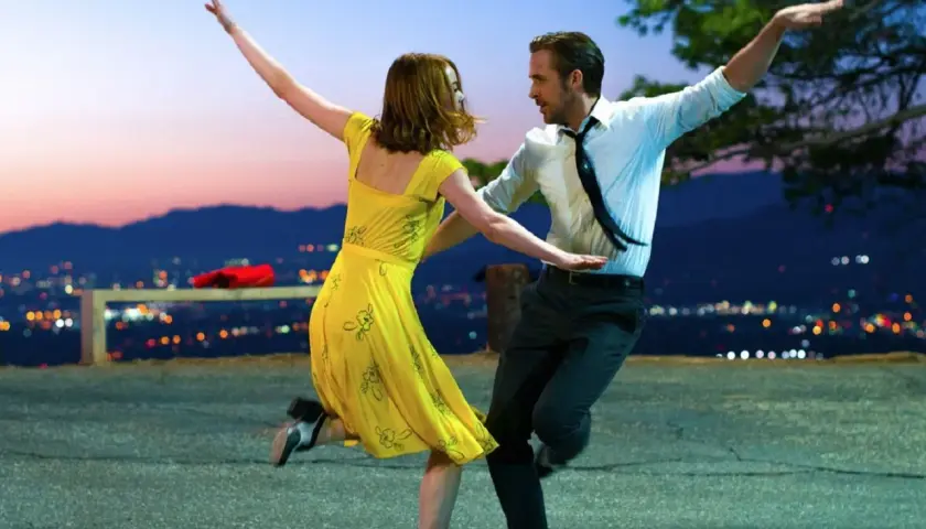 Ein Paar tanzt im Abendrot vor einer Stadtkulisse. Perfekt für gute Laune Filme!