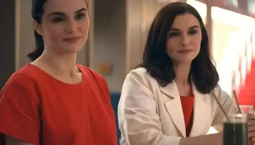 Zwei Frauen, die sich ähneln, stehen nebeneinander. Die eine trägt ein rotes Oberteil, die andere einen beigen Blazer über einem roten Kleid. Sie sind Teil von "die unzertrennlichen serie".