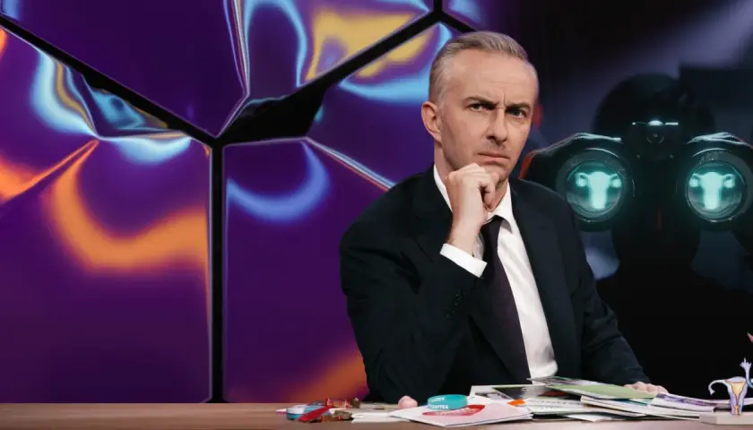 Mann mit nachdenklichem Blick hinter einem Schreibtisch, im Hintergrund eine abstrakte, bunte Wand und ein Fernglas mit seltsamen Symbolen, die wie gibberish language wirken.