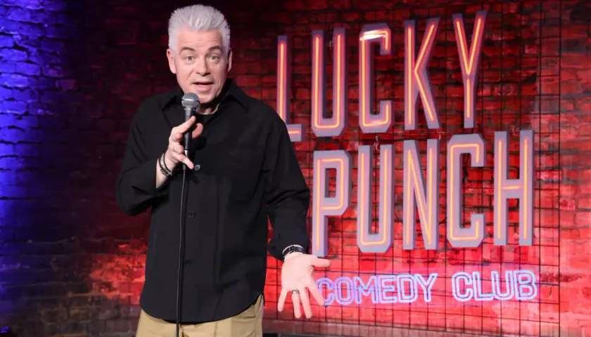 Ein Comedian mit grauem Haar steht auf der Bühne des "Lucky Punch Comedy Club" und erzählt Witze.