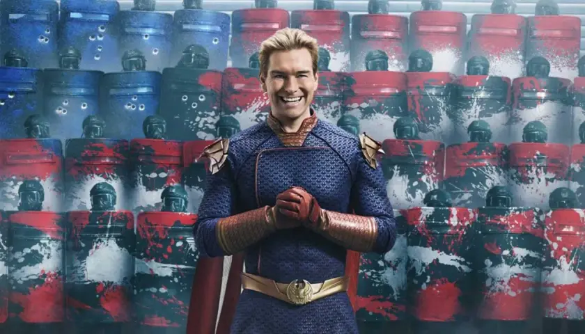 Homelander, Teil der Besetzung von The Boys, steht vor einer Reihe von Riot-Schutzschilden, die mit roten und blauen Farbspritzern verziert sind.