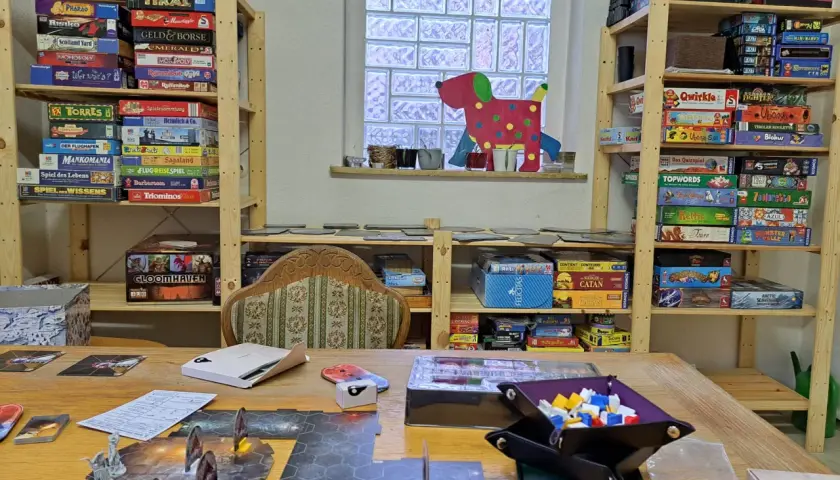 Regale voller Brettspiele für sprachspiele erwachsene. Ein Spielbrett mit Figuren liegt auf dem Tisch.