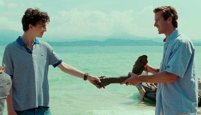 Besetzung von Call Me By Your Name: Elio und Oliver am See, Oliver hält eine Statue.