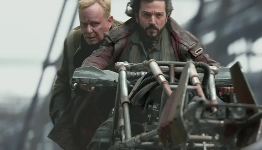 Zwei Männer auf einem Motorrad in der Serie "Andor". Der Fahrer blickt entschlossen, der Beifahrer besorgt.