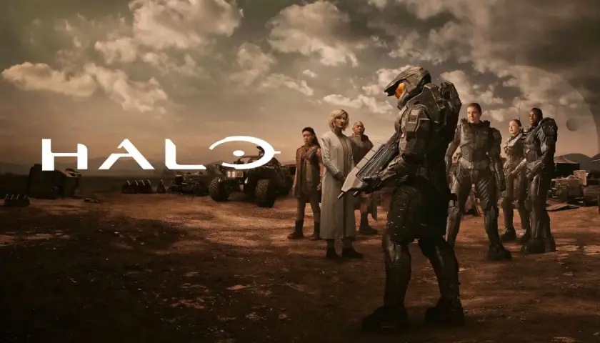 Die Besetzung von Halo (Fernsehserie) steht in einer staubigen Landschaft. Im Vordergrund ein Master Chief, im Hintergrund das Halo-Logo und weitere Charaktere.