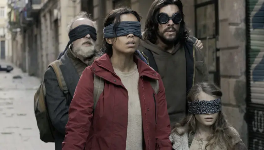 Die Besetzung von Bird Box: Eine Gruppe von Menschen, die mit verbundenen Augen durch eine Gasse gehen, um den unsichtbaren Gefahren zu entkommen.
