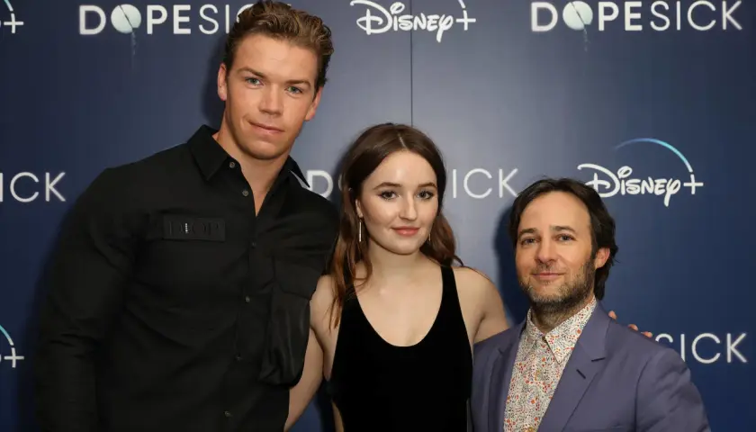 Die Besetzung von Dopesick: Will Poulter, Kaitlyn Dever und Michael Keaton posieren vor dem Disney+ Logo.