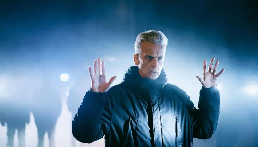 Mann mit grauen Haaren und ernstem Blick, hebt die Hände. Nebel und Lichter im Hintergrund deuten auf die Teufelsstunde hin.