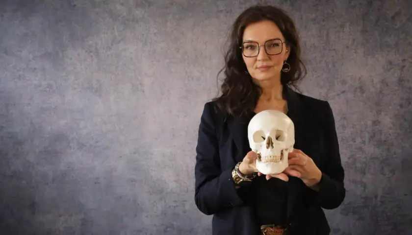 Frau mit Brille hält Totenkopf. Ein gutes stegreifrede beispiel, um über Vergänglichkeit zu sprechen.