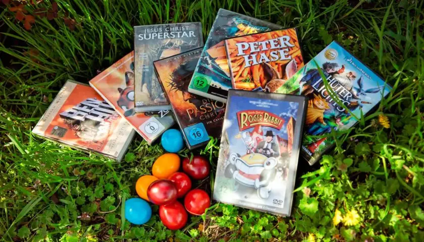 Osterfilm-Spaß für Kinder: DVDs wie "Peter Hase" und "Roger Rabbit" liegen neben bunten Eiern im Gras.