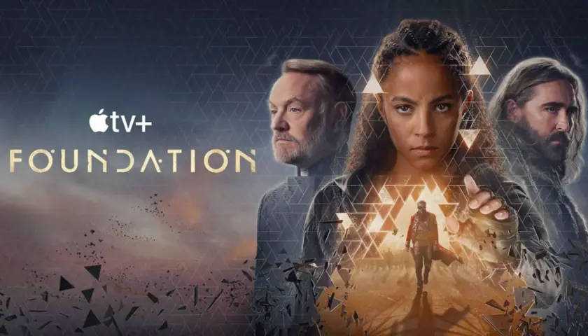 Apple TV+ "Foundation" Serie: Drei Hauptfiguren blicken ernst in die Ferne, während ein Mann im Vordergrund eine Hand ausstreckt.