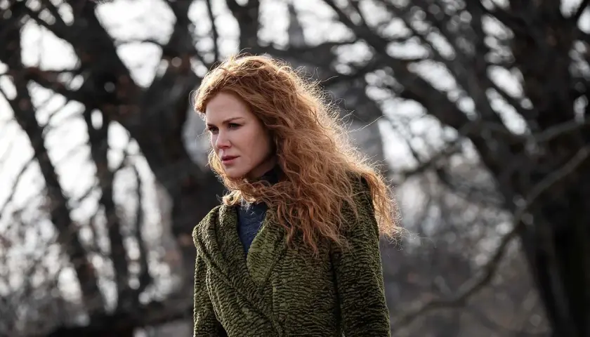 Nicole Kidman mit roten Haaren, im grünen Mantel, blickt nachdenklich in die Ferne. Ein Moment des "the undoing" in der Natur.