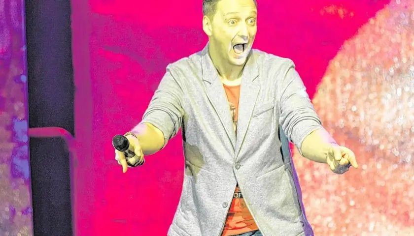 Ein Mann mit offenem Mund und Mikrofon in der Hand, der eine lebhafte Performance liefert – das ist die Essenz von Kabarett.