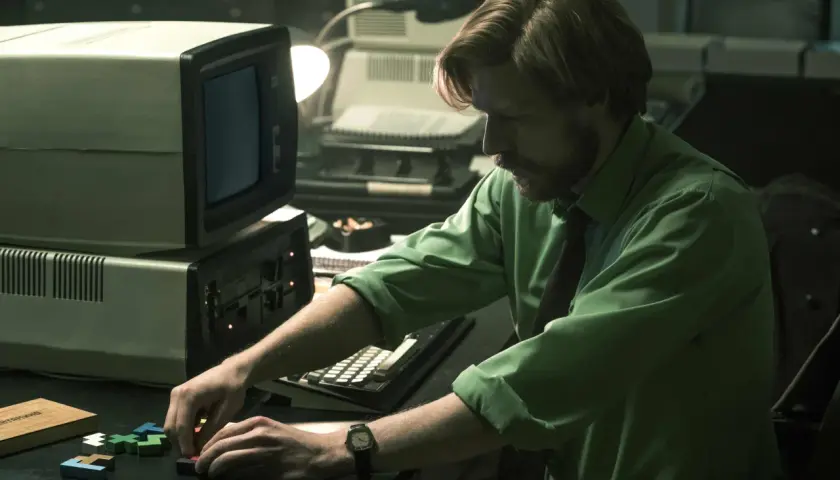 Mann mit Bart spielt mit Tetris-Steinen vor einem alten Computer. Ein Moment aus dem "Tetris"-Film.