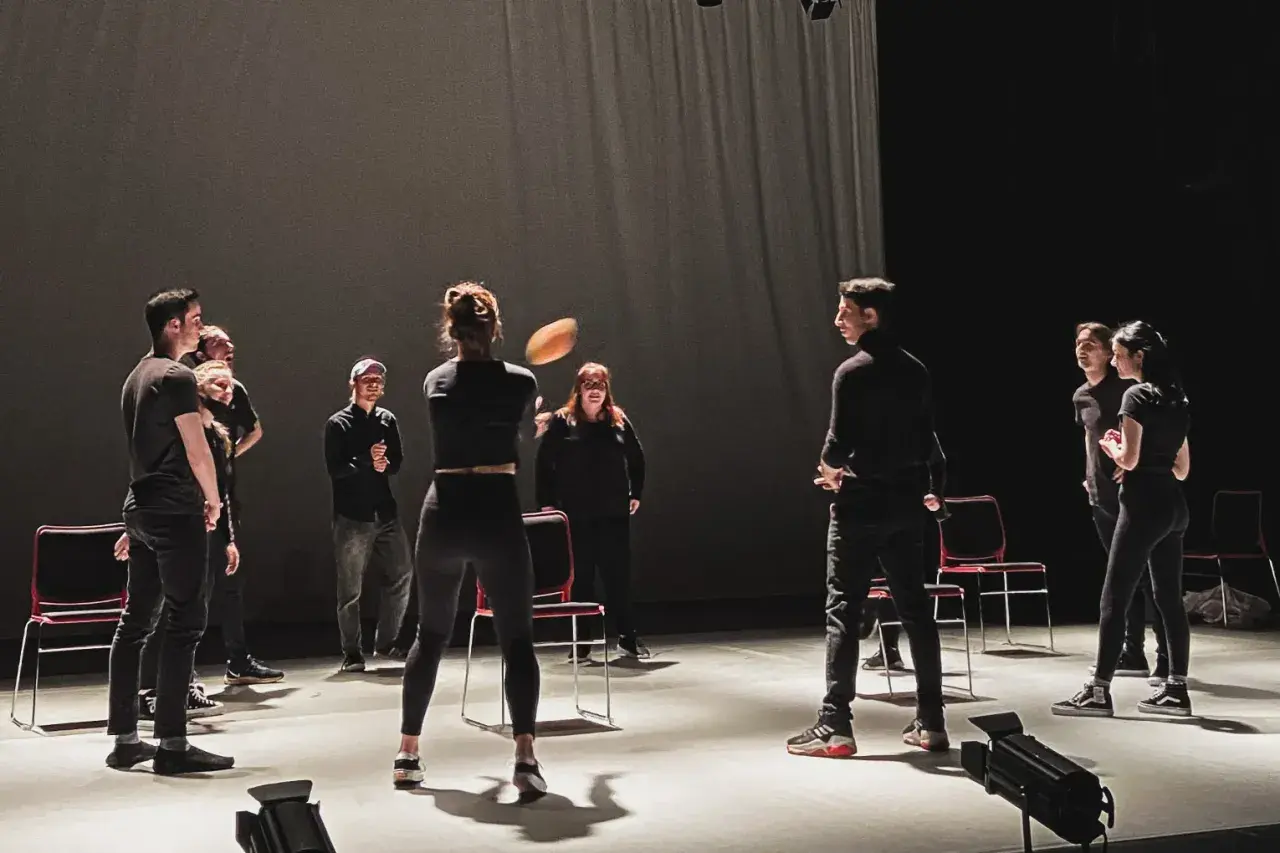 Schauspieler proben auf der Bühne, eine Frau wirft einen Ball. Viele improtheater ideen entstehen in solchen Momenten.
