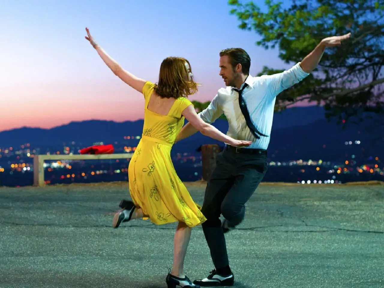 Ein Paar tanzt im Abendrot vor einer Stadtkulisse. Perfekt für gute Laune Filme!